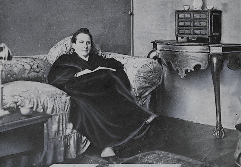 Gertrude Stein sitting on a sofa in her Paris studio